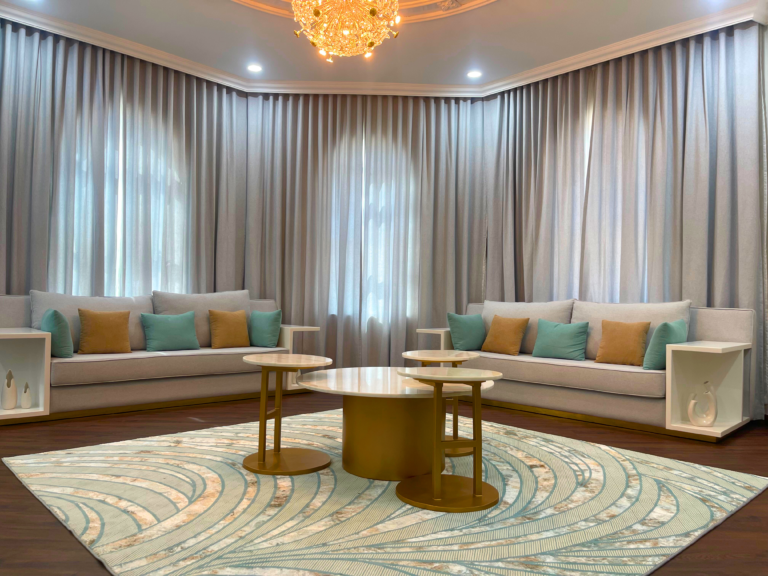 Majlis with beige sofas, gold nesting tables and arched curtains by Al Malek Carpentry, Ras Al Khaimah