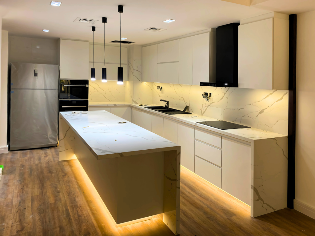 White kitchen with LED-lit island and pendant lights by Al Malek Carpentry, Ras Al Khaimah