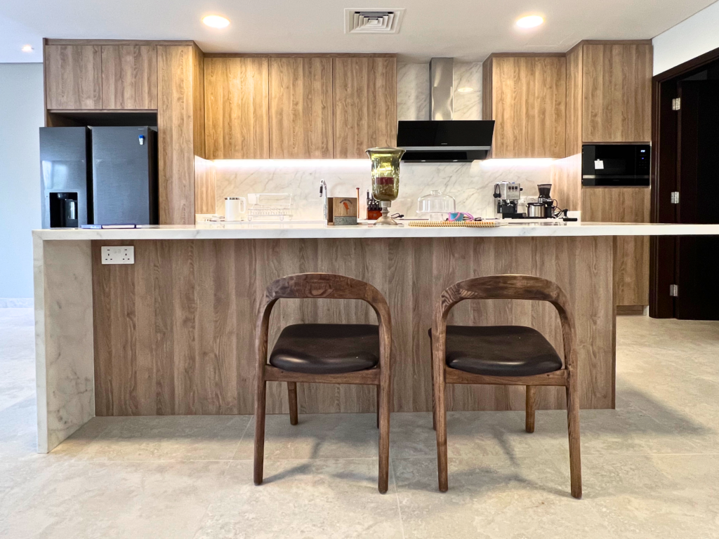Wood-look kitchen with breakfast island and bar chairs by Al Malek Carpentry, Ras Al Khaimah