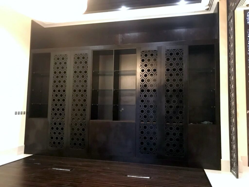 Dark wood display cabinet with CNC-cut Islamic star mashrabiya doors, by Al Malek Carpentry