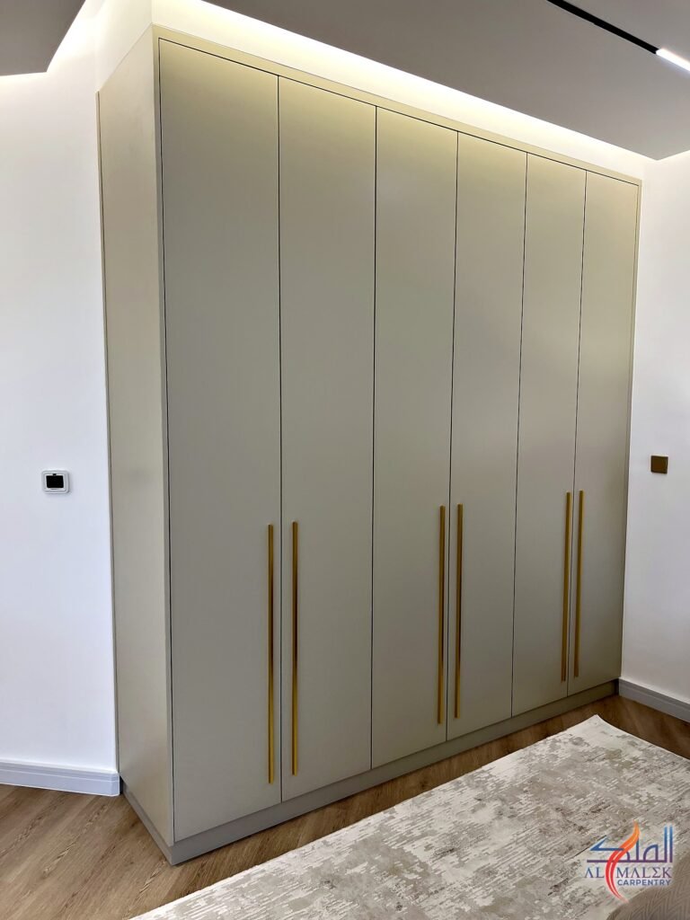 Full-height six-door built-in wardrobe in matt greige with long gold bar handles, Bab Al Bahar penthouse, Al Malek Carpentry