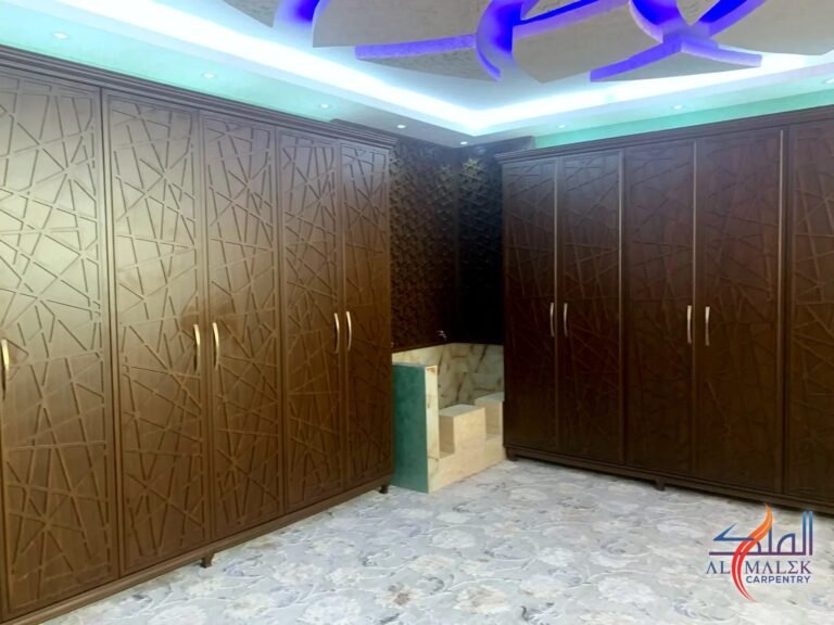 Wardrobe wall with CNC-cut geometric pattern doors and a mashrabiya corner panel, made by Al Malek Carpentry