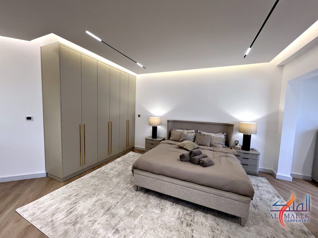 Penthouse master bedroom in Bab Al Bahar, Ras Al Khaimah, with a full-height built-in wardrobe, upholstered bed and LED cove ceiling by Al Malek Carpentry